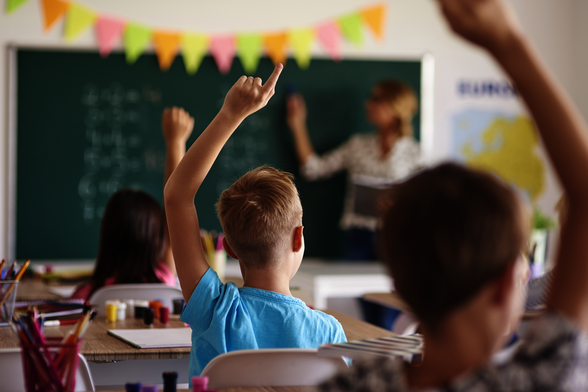 Kinder in einem Klassenzimmer, die sich mit Handzeichen melden
