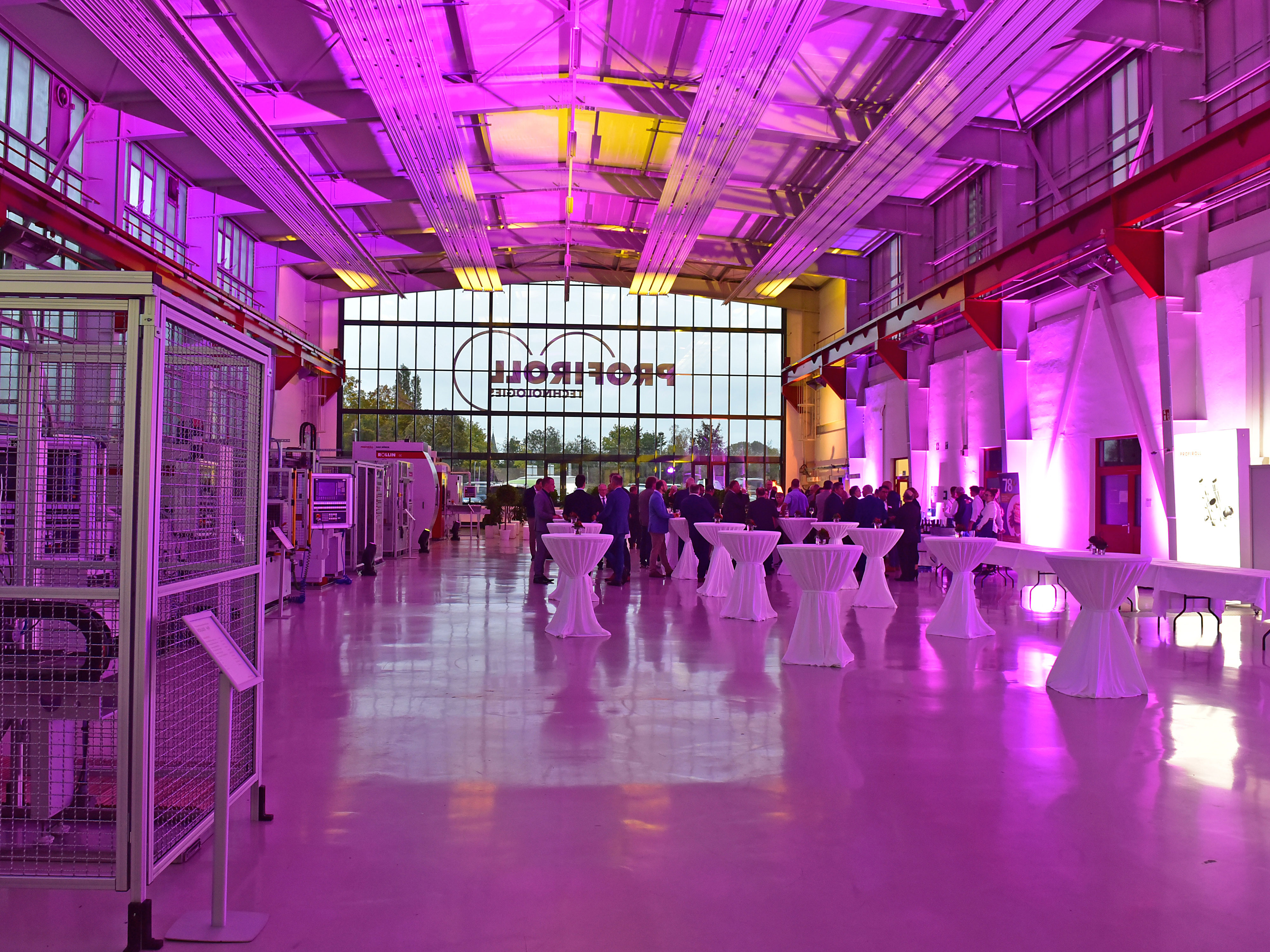 Große Fabrikhalle, pink ausgeleuchtet, mit festlichen Stehtischen